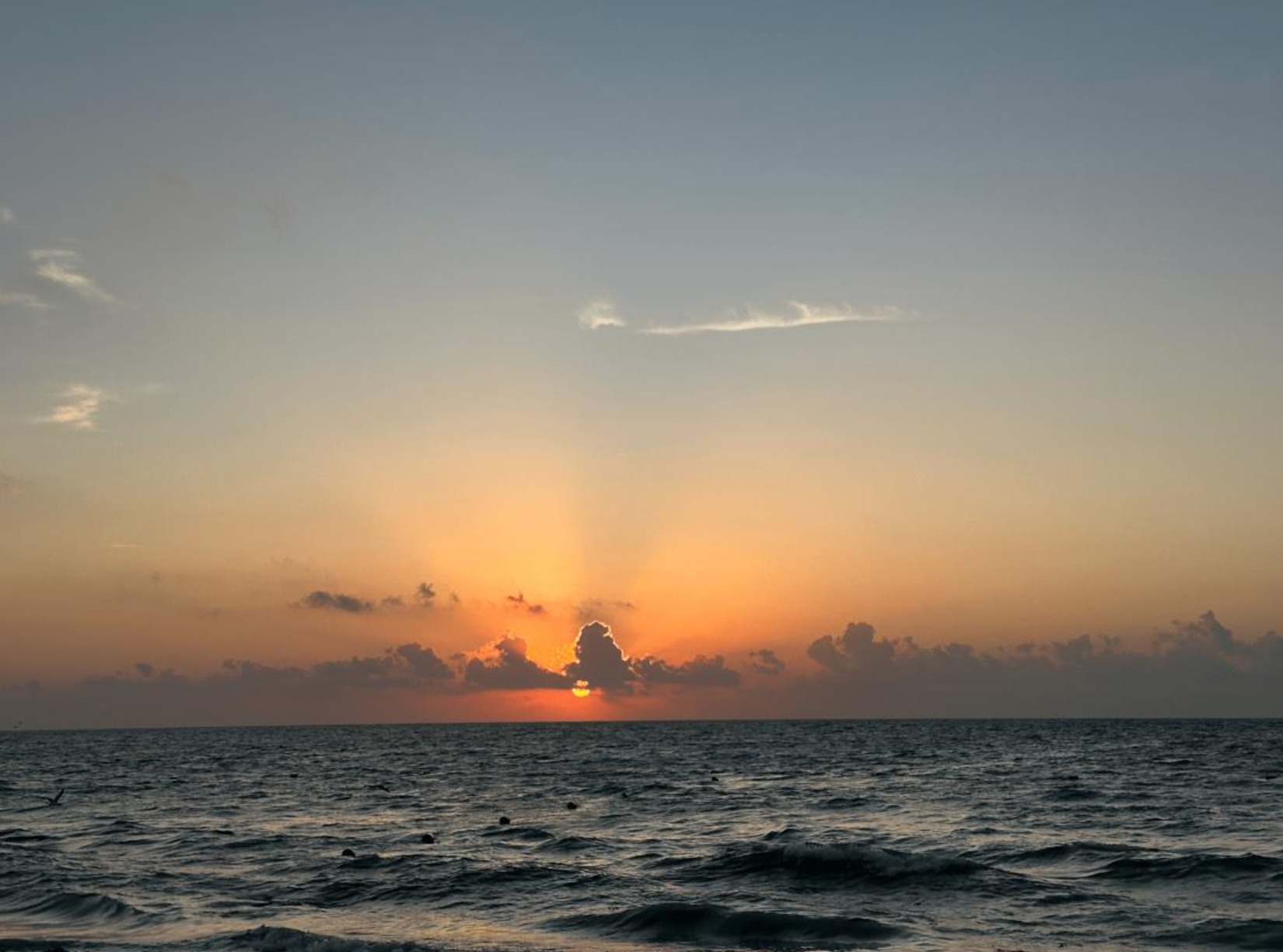 Sunrise over the ocean with calm waves and soft sky colors