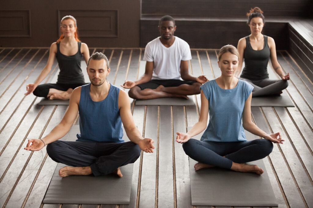 Group of people practicing seated meditation indoors on yoga mats