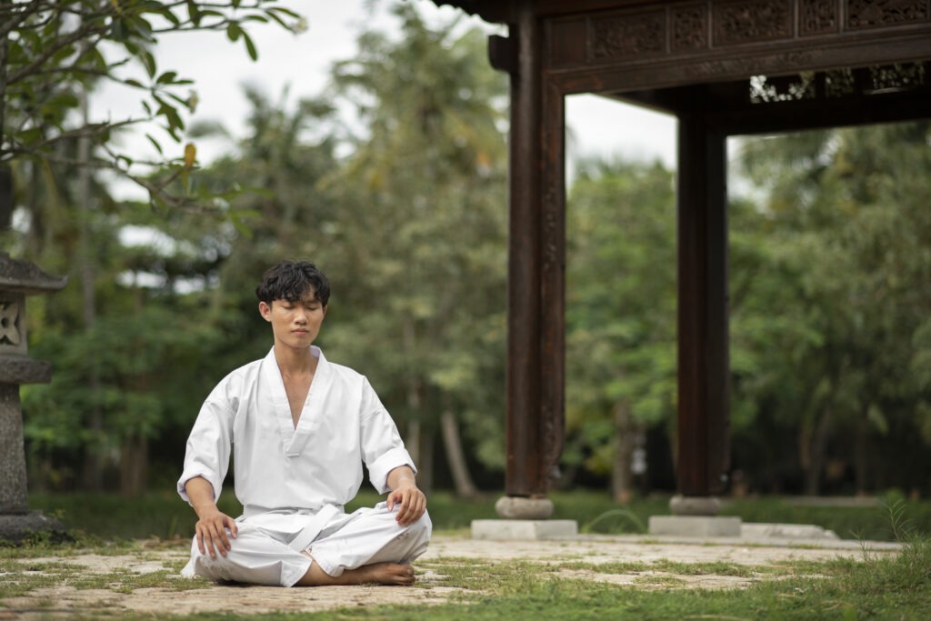 Man in white clothing meditating in a peaceful zen garden setting