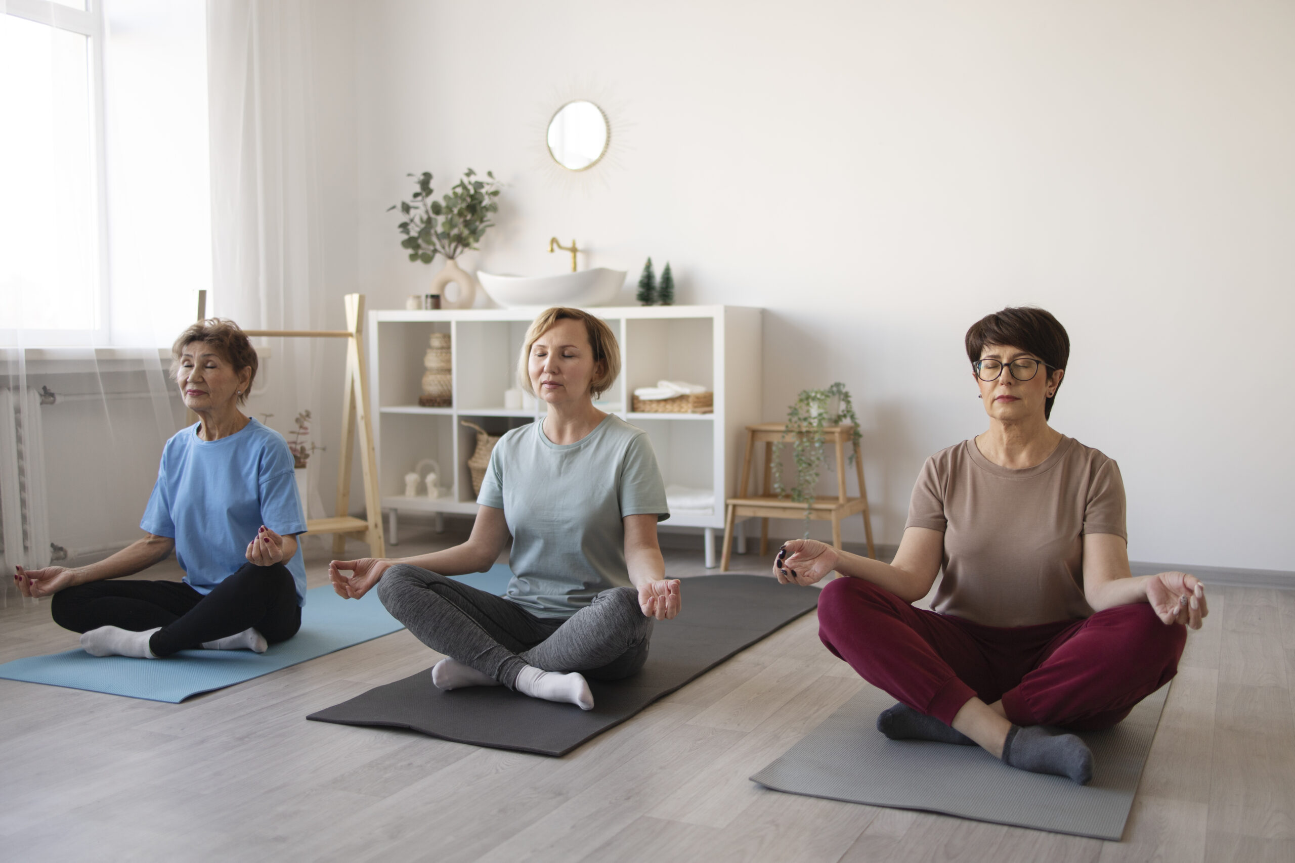 Group of women practicing seated meditation indoors on yoga mats